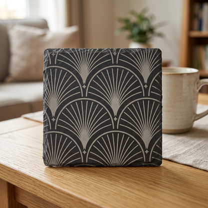 Square slate coaster with an engraved fan pattern on an oak coffee table