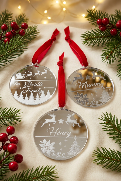 Three personalised silver mirrored Christmas decorations with festive greenery